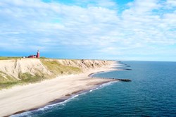 Panoramic aerial view of Bovbjerg Fyr lighthouse, cliffs and North Sea in summer with blue sky