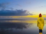 Frau mit gelber Regenjacke am Meer