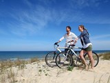 Pärchen steht mit Fahrrädern auf einer Sanddüne