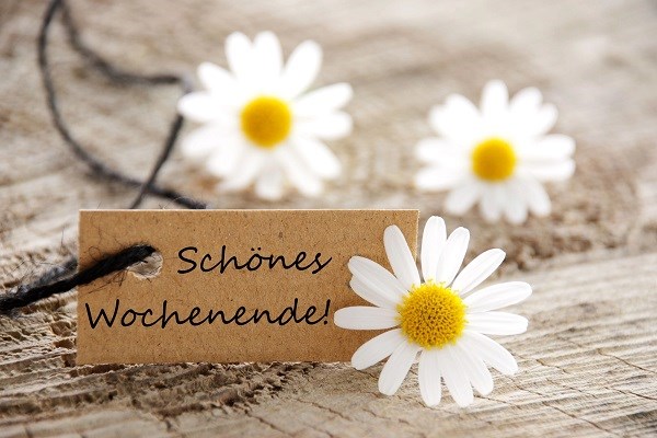 Ein Schönes-Wochenende-Schild und weiße Blumen auf einem Holzhintergrund