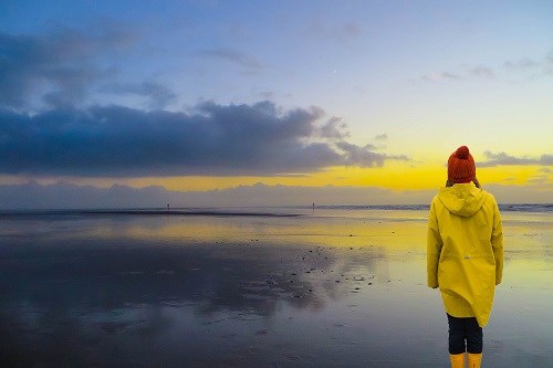 Frau mit gelber Regenjacke am Meer