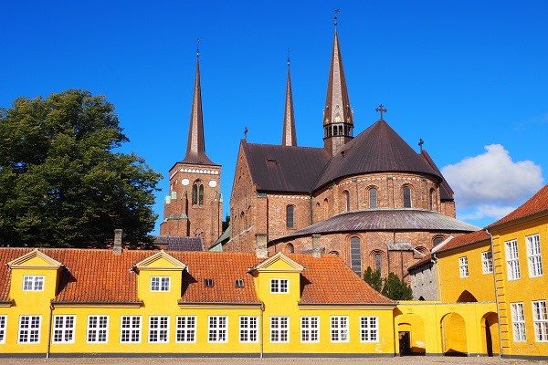 Der Dom zu Roskilde mit gelben Häusern im Vordergrund