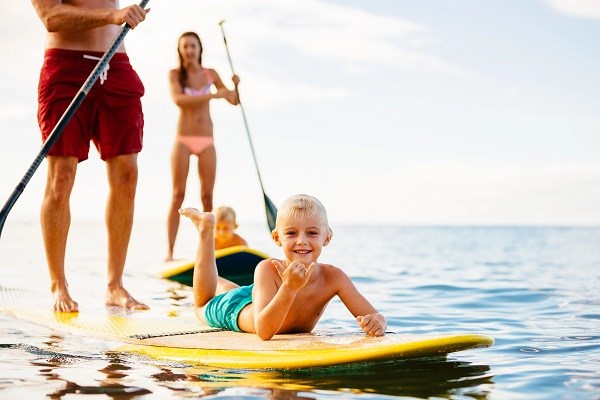 Eine fröhliche Familie mit zwei Jungs auf SUP-Boards