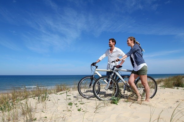 Pärchen steht mit Fahrrädern auf einer Sanddüne