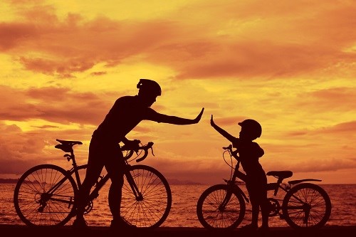 Vater mit Sohn auf dem Fahrrad vor Sonnenuntergaben machen „give me 5“