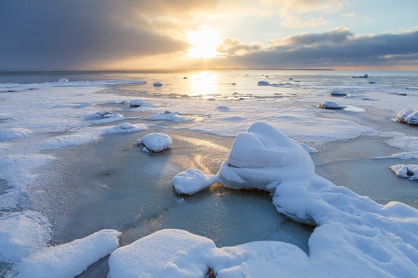 Zugefrorene Ostsee am Strand mit Steinen und Schnee