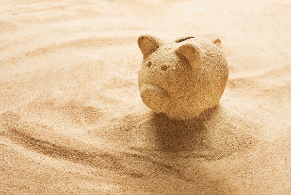 Ein Sparschwein am Sandstrand - was darf der Urlaub kosten