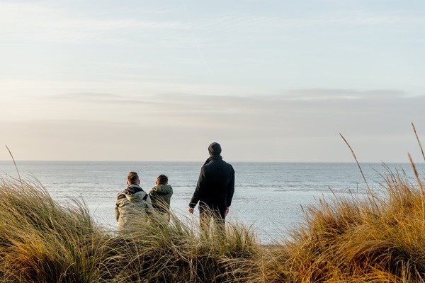 2 Männer und ein kleiner Junge schauen auf das Meer in Blåvand