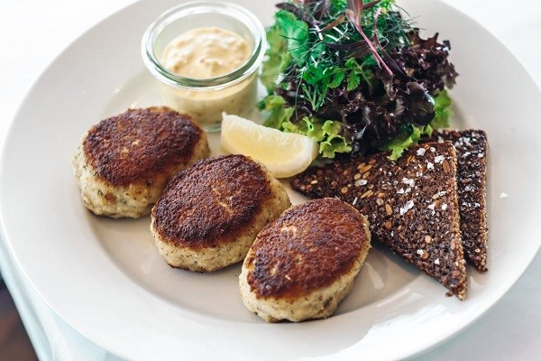 Drei Frikadellen auf einem Teller mit Roggenbrot und Salat