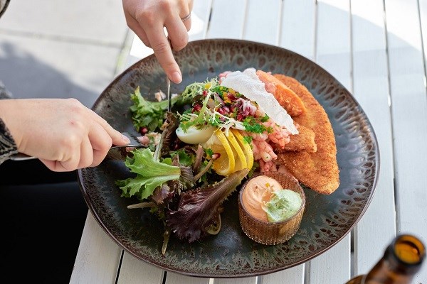 Ein Fischteller mit Roggenbrot, paniertem Schollenfilet, Garnelen und Salat