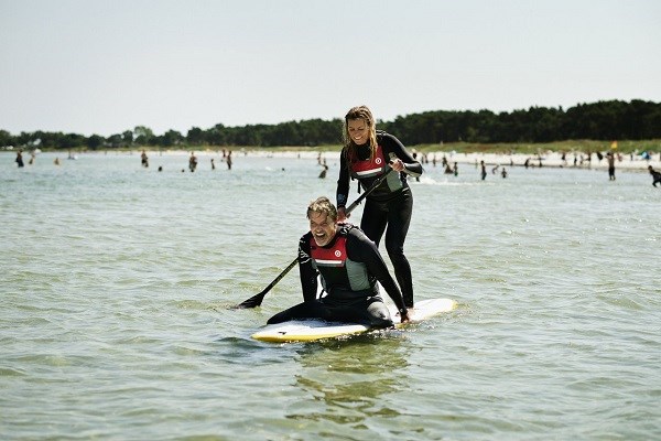 Ein Mann und eine Frau haben Spaß auf einem SUP-Board in Dänemark