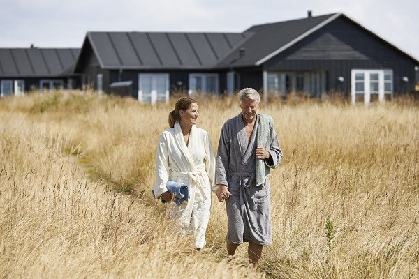 Ein Paar in Bademänteln mit einem Ferienhaus im Hintergrund in Nysted auf Lolland