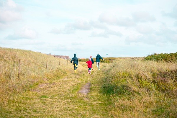 Kinder, die zwischen den Dünen an der dänischen Nordsee bei Blavand laufen