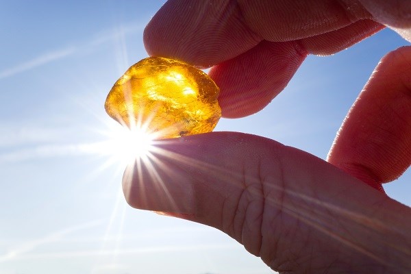 Männliche Hand hält Bernstein gegen die Sonne