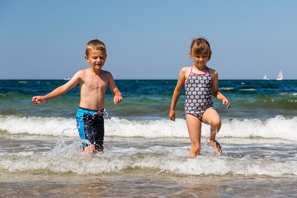 Zwei kleine Kinder spielen fröhlich im Wasser bei Blokhus